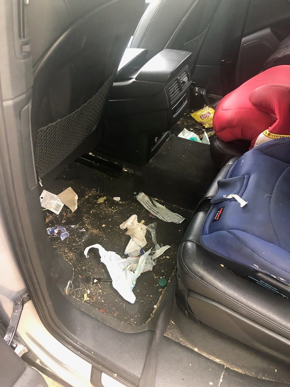 Family SUV interior before a detail, with crumbs and everyday mess in the seats