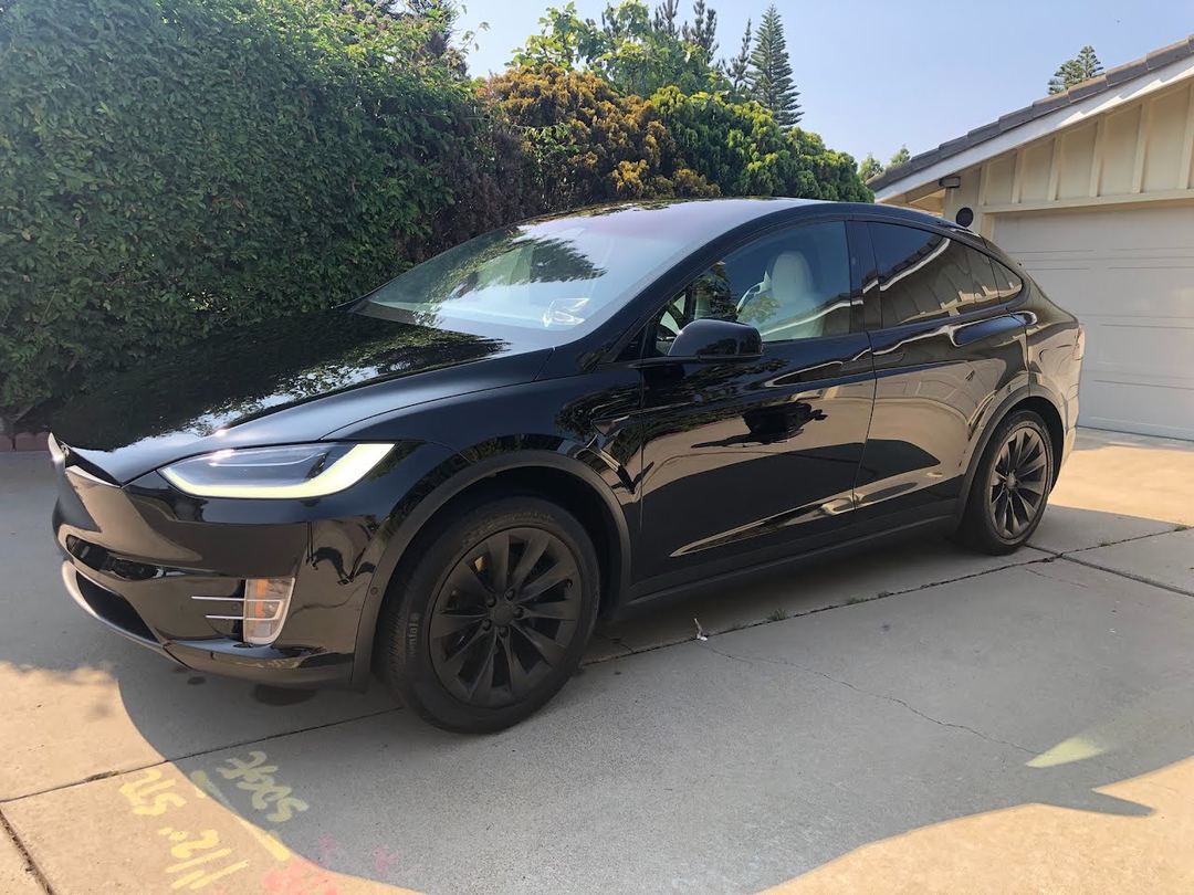 Black Tesla Model X gleaming in a driveway after The Bling exterior detail