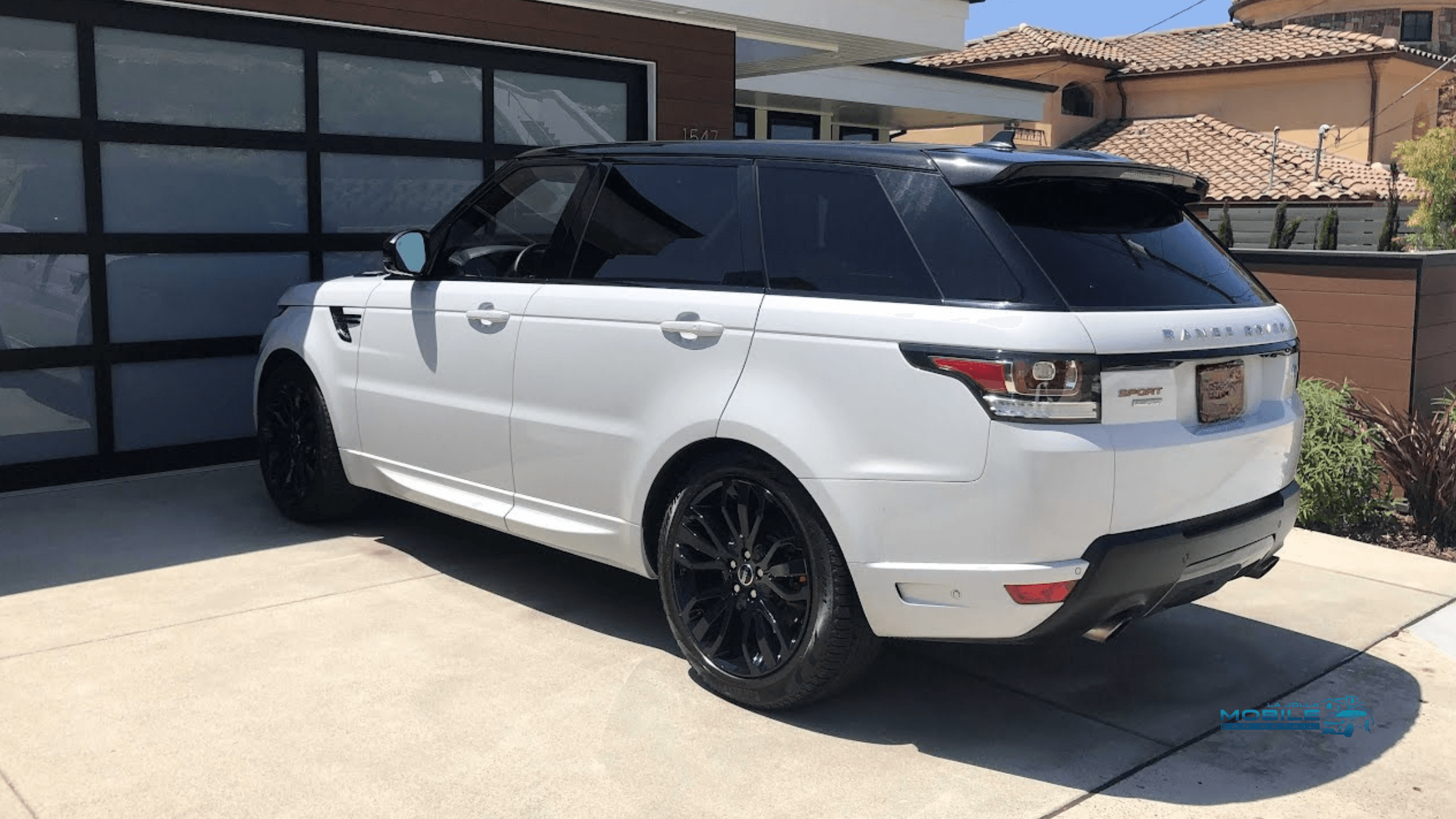 A pristine white Range Rover Sport after a professional car cleaning, parked in a modern La Jolla driveway following a mobile car detailing service in San Diego.
