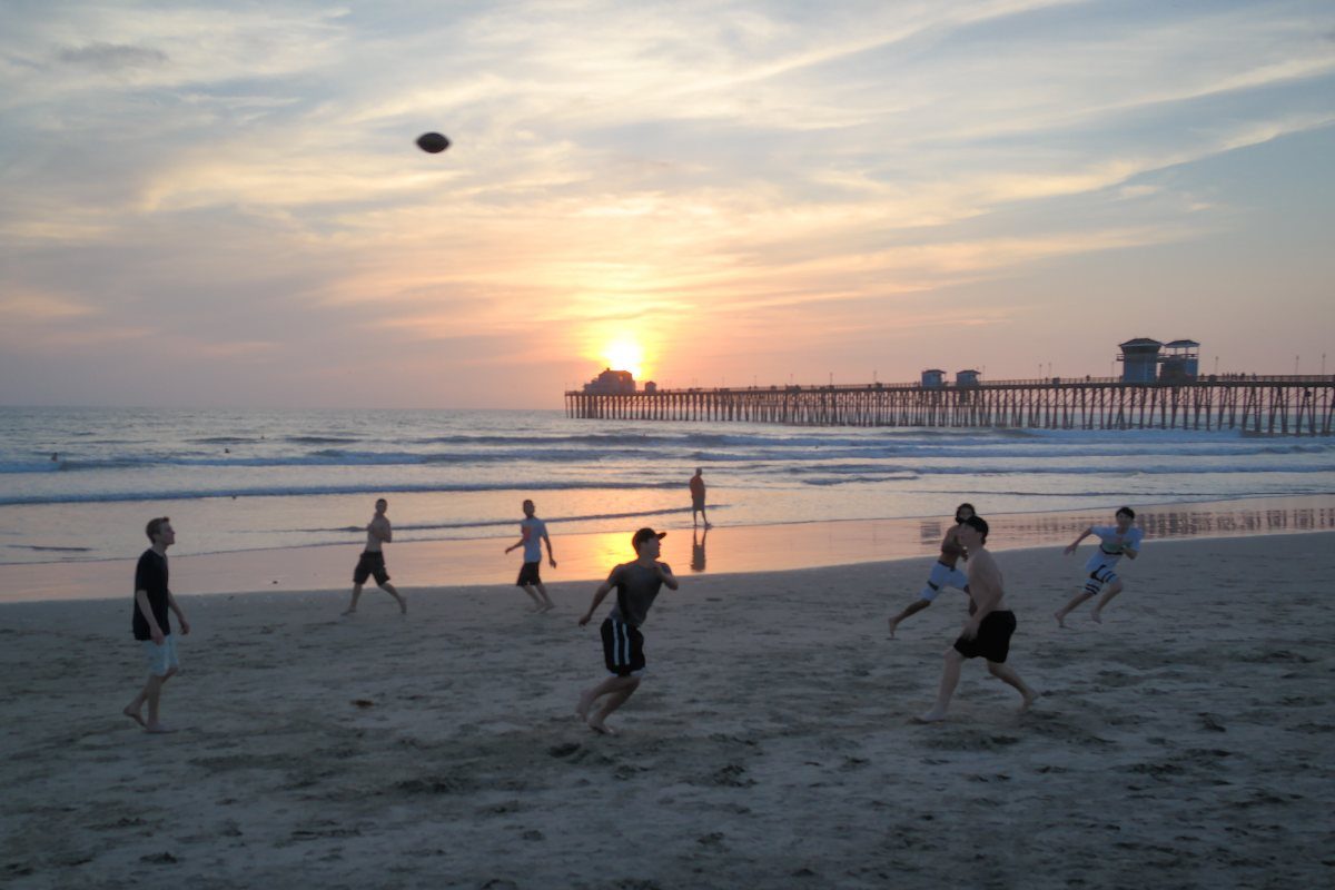 Beach football on the sand in front of the Oceanside Pier at sunset